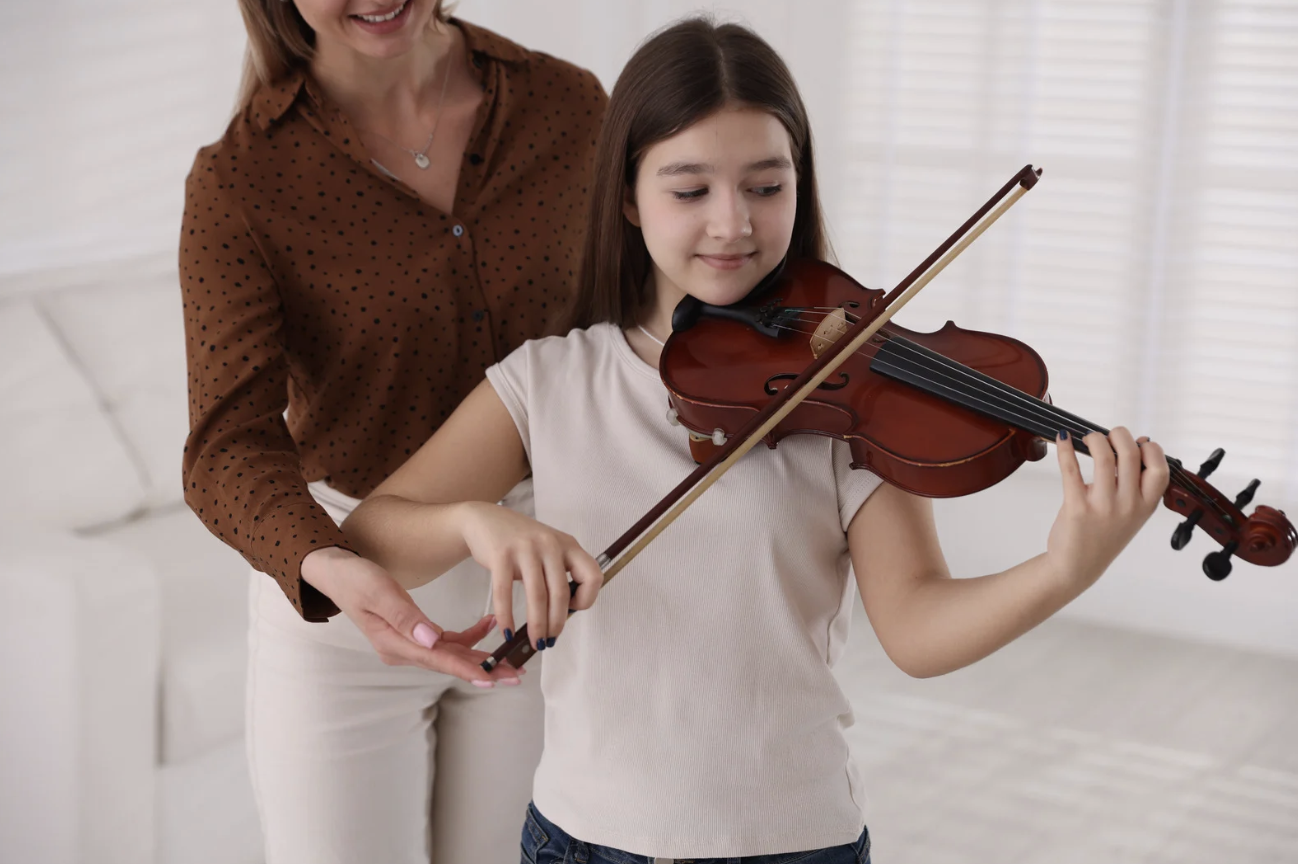 Strings instructor guiding a young student's bow hold during a private lesson